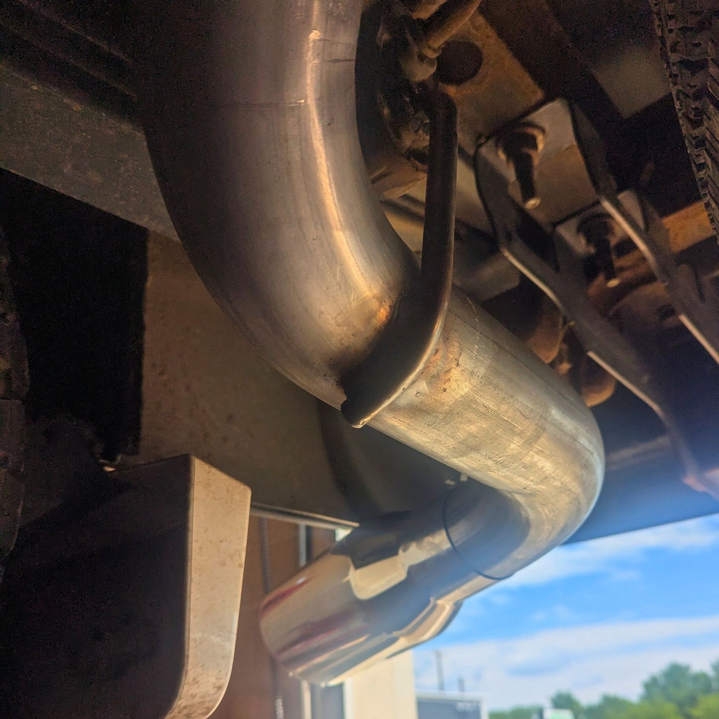 Close-up of a GMC Sierra exhaust tip mounted on truck.